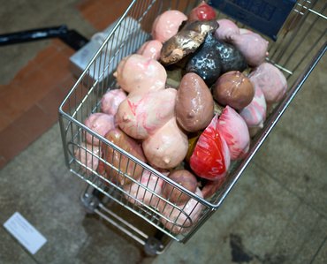 a shopping cart filled with women's breasts at an exhibition in Keskturg symbolizing exploitation of refugee women