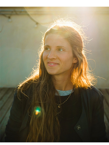 Die Fotografin Juliane Sommer steht im goldenen Gegenlicht und schaut freudig seitlich zur Kamera. 