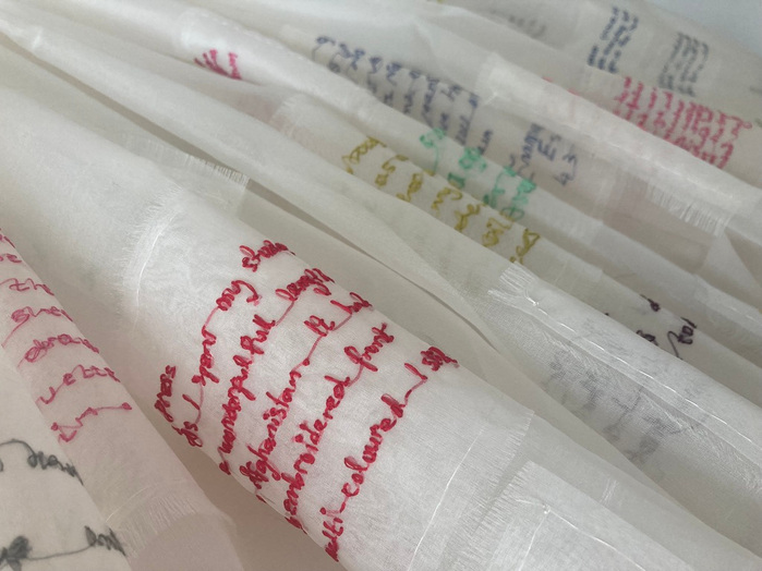 Detail of Fragment of a dress, showing the embroidered lettering on transparent ivory coloured silk.