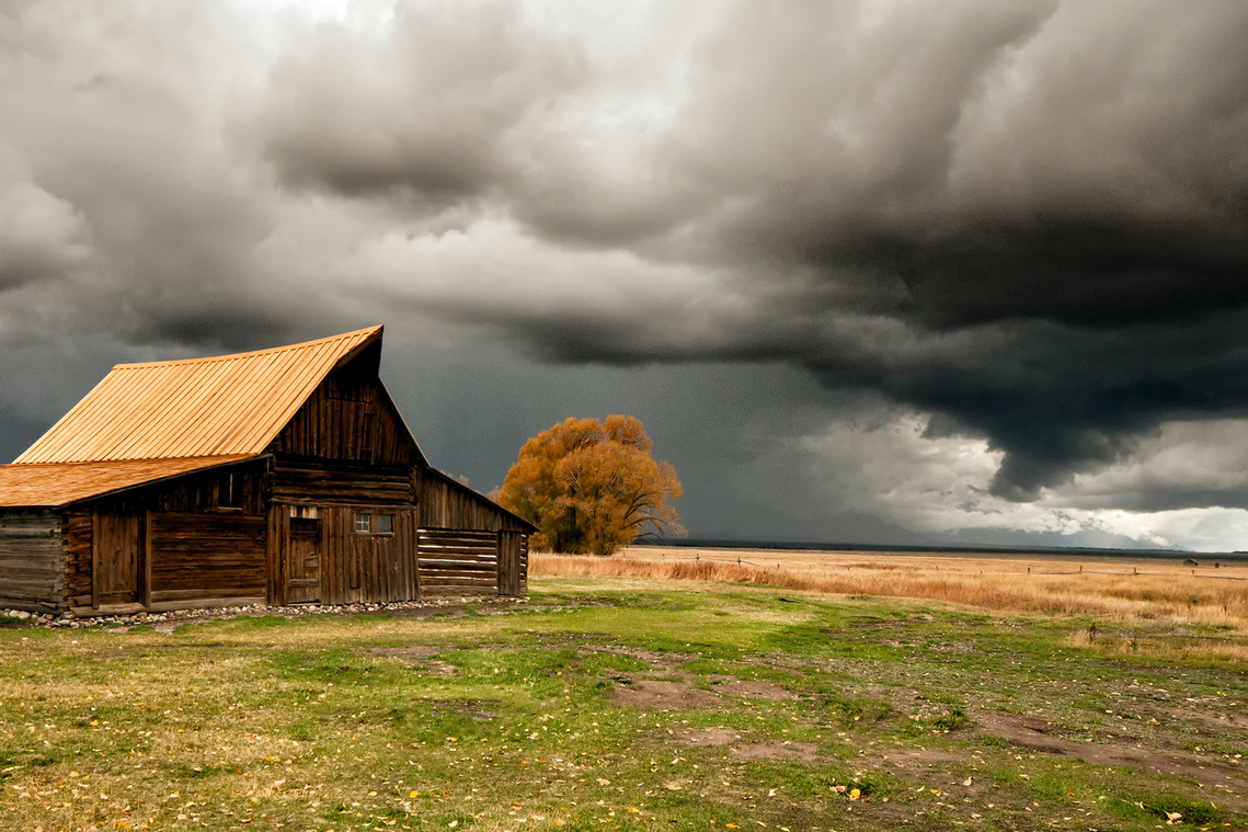 Prairie barn under cloudy sky.
