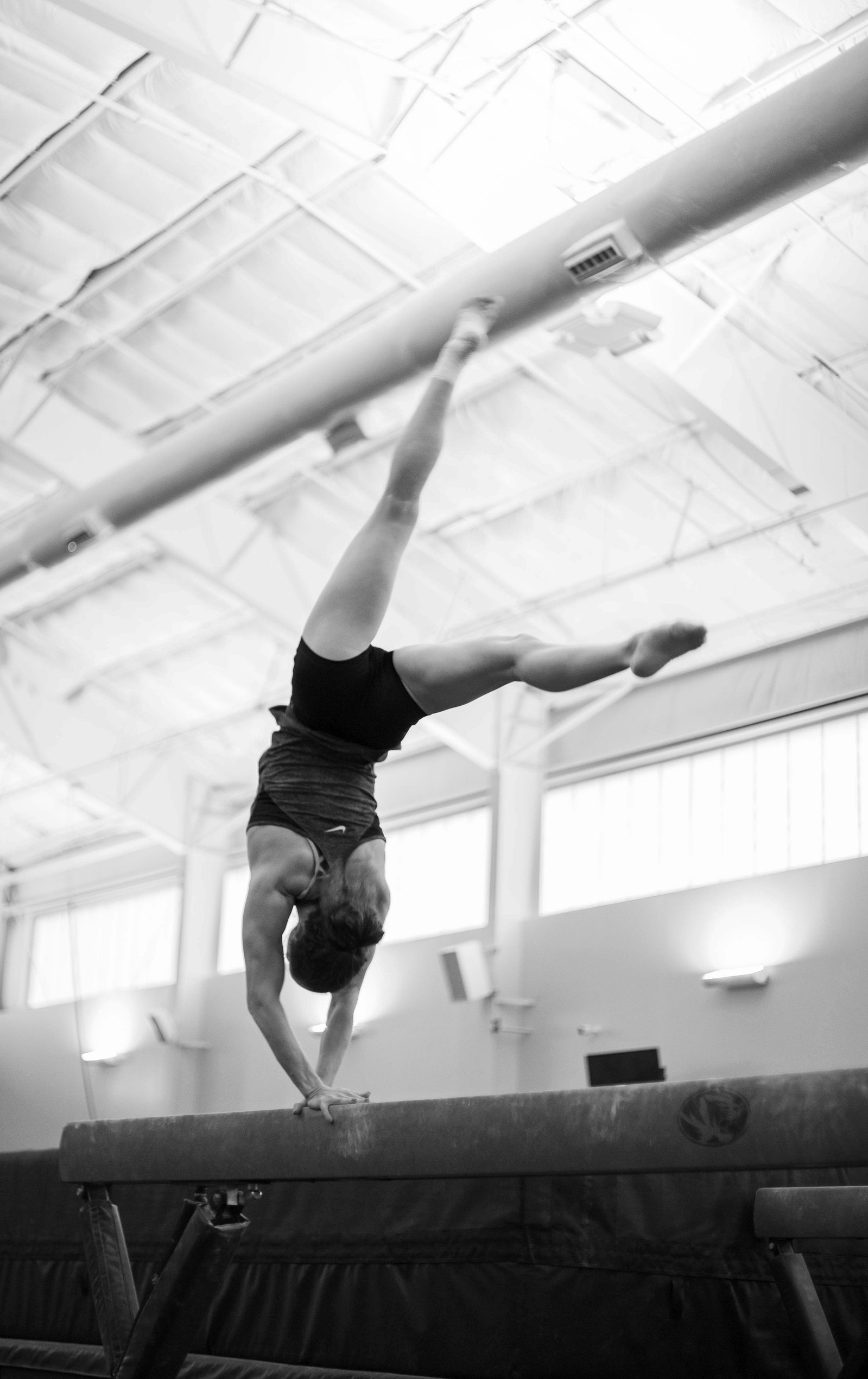 A gymnast does a back handspring on a beam. (Kate Trabalka Photography)