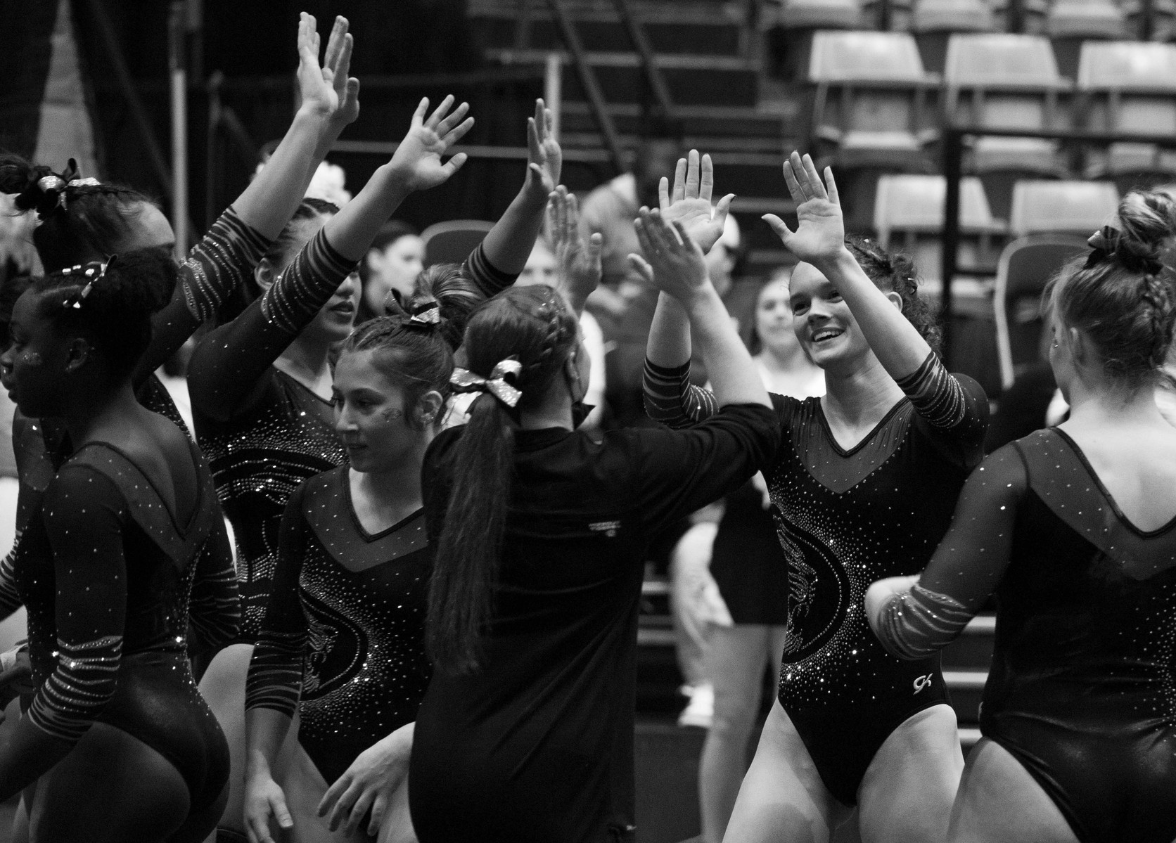 A gymnast's teammates high five her after her floor performance. (Kate Trabalka Photography)