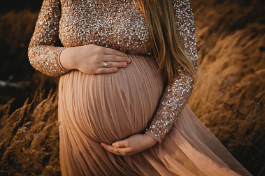 Beim Babybauch-Fotoshooting in Berlin posiert die werdende Mutter in einem eleganten Schwangerschaftskleid für die Fotografin.