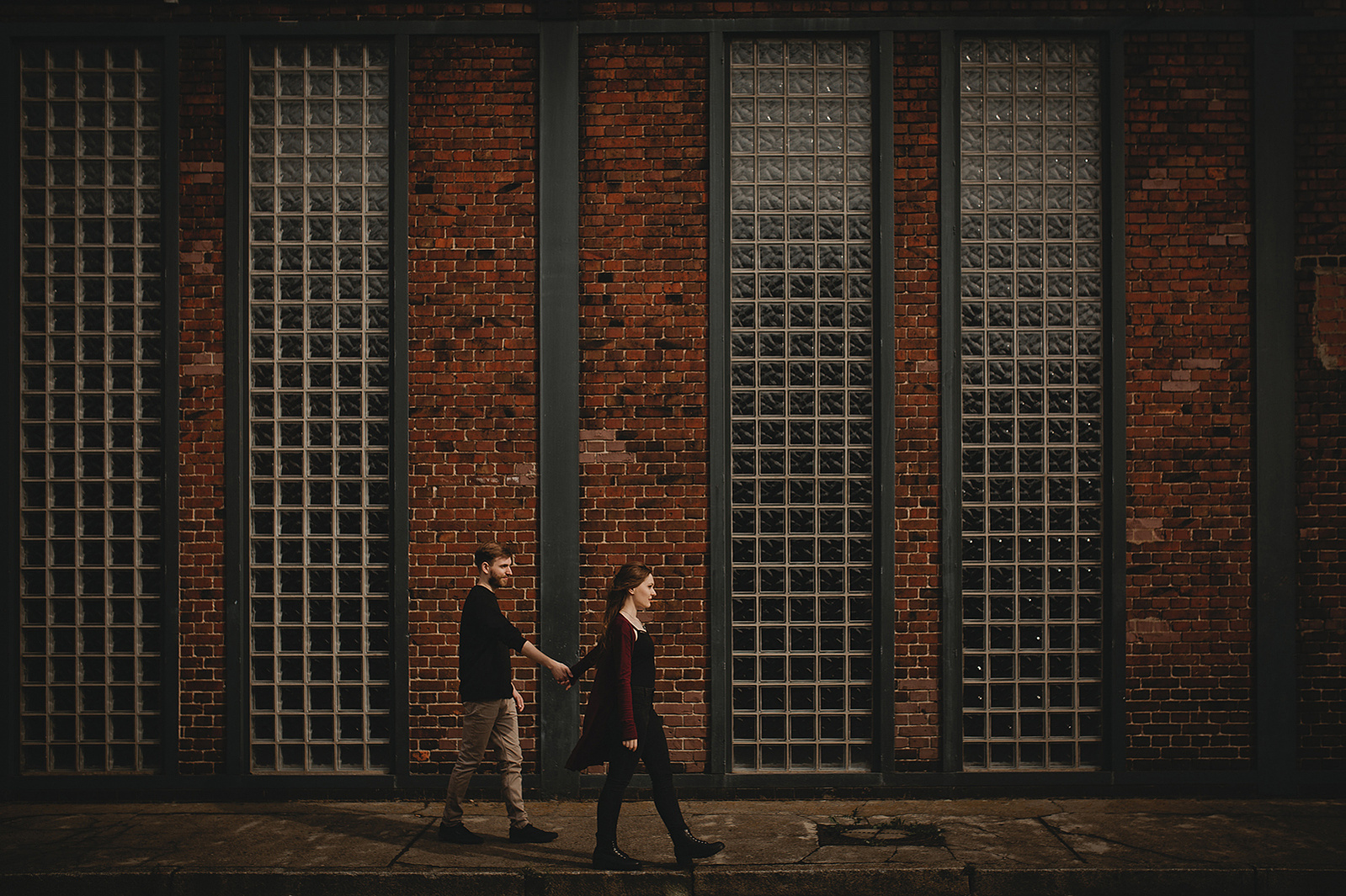 Paar läuft beim Fotoshooting in Berlin Hand in Hand durch Industriegebiet 