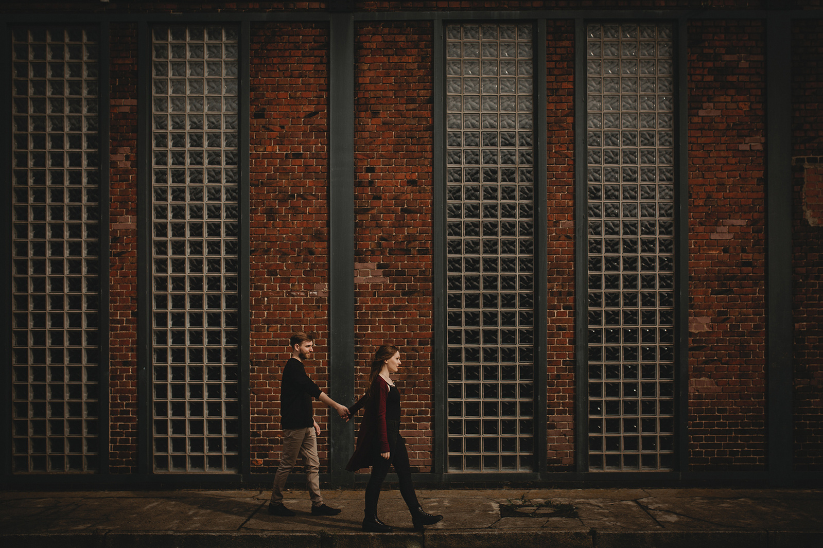 Paar läuft beim Fotoshooting in Berlin Hand in Hand durch Industriegebiet 