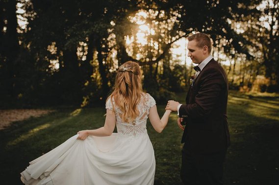 Eine Braut im boho Hochzeitskleid tanzt zur Golden Hour mit ihrem Ehemann auf einer Wiese in Bad Saarow.
