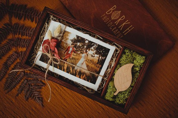 Gravierte Holzbox mit Hochzeitsfotos auf einem USB Stick und Fotoabzügen von einer Hochzeitsfotografin aus Berlin.