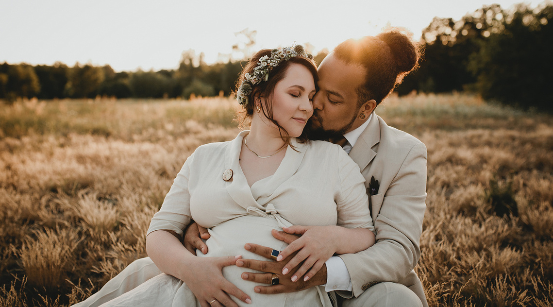 Hochzeitspaar sitzt bei Brautpaarshooting in Brandenburg für Hochzeitsfotos im Sonnenuntergang auf Wiese