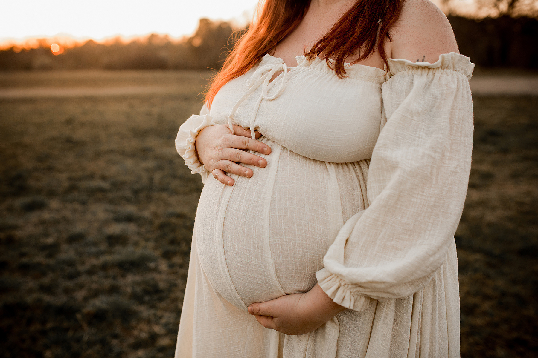 Detailaufnahme von einem Fotoshooting in der Schwangerschaft in Berlin. Eine Frau streichelt ihren Babybauch. 