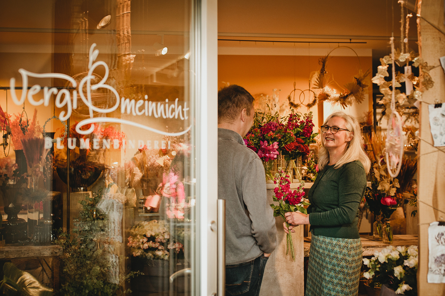 Authentisches Businessfoto von einer Floristin im Gespräch mit einem Kunden in ihrem Geschäft in Berlin. 