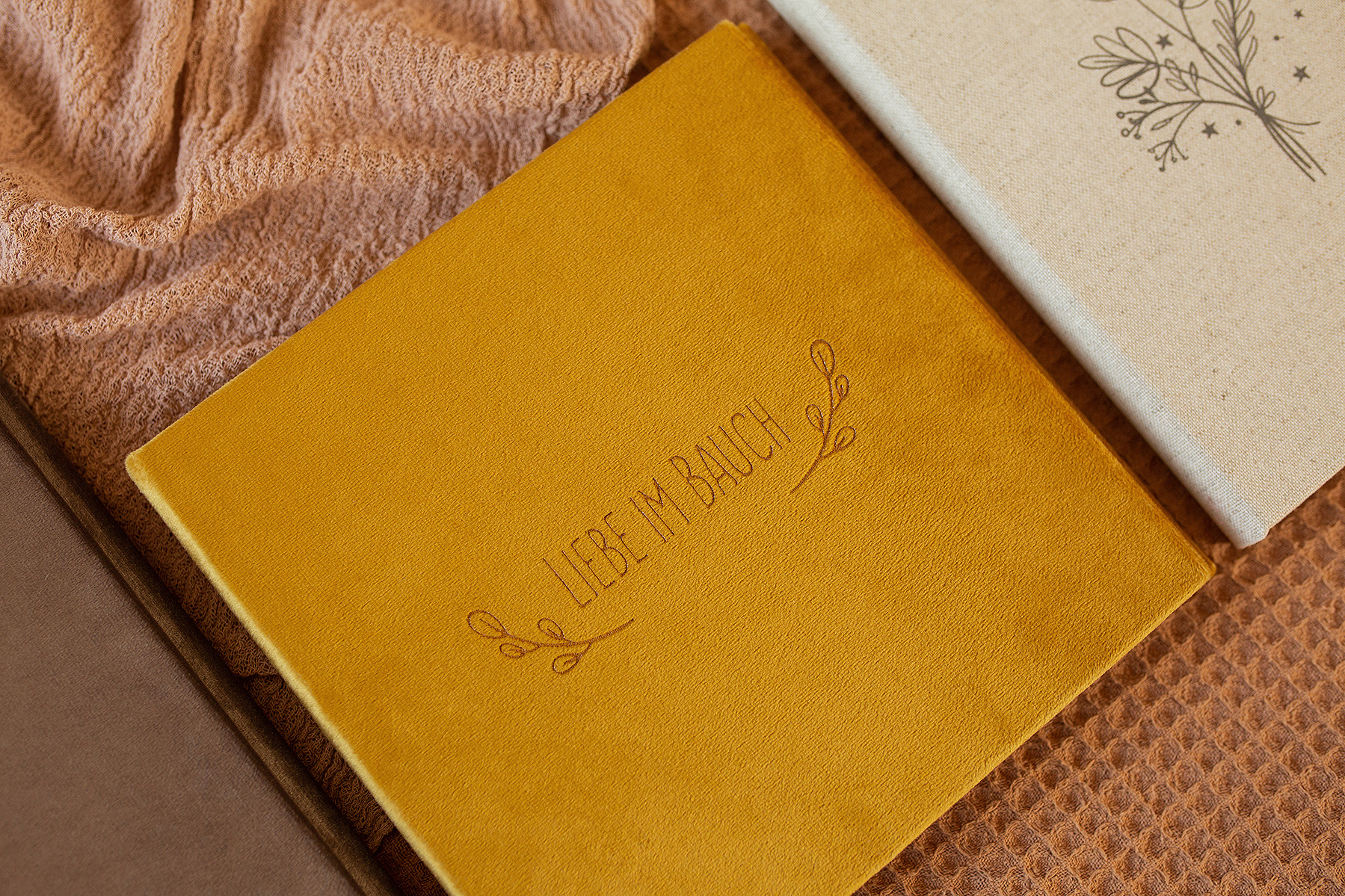 Ein Fotoalbum von einem Babybauchshooting mit senfgelbem Samtbezug und dem Schriftzug "Liebe im Bauch".