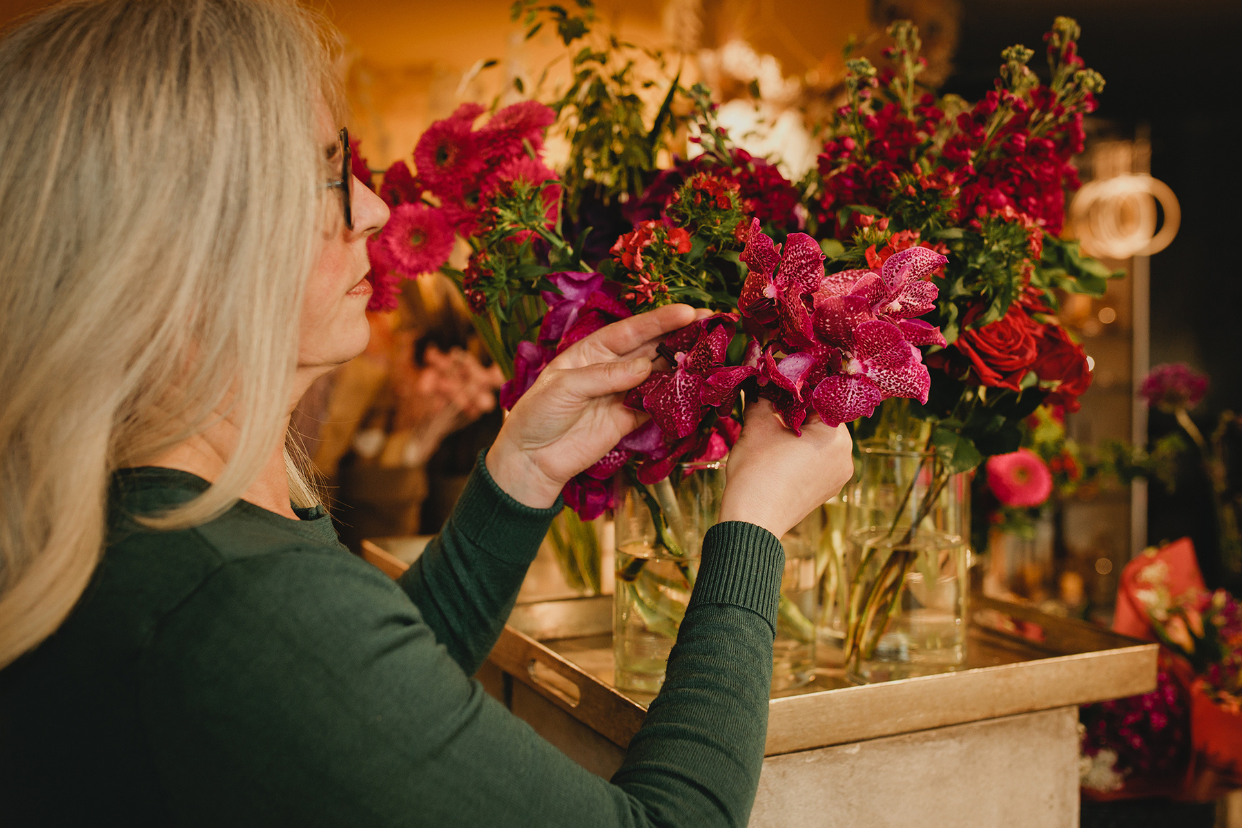 Eine Floristin arrangiert die Blumen in ihrem Laden, während die Businessfotografin aus Berlin ungestellte Fotos von ihr macht. 