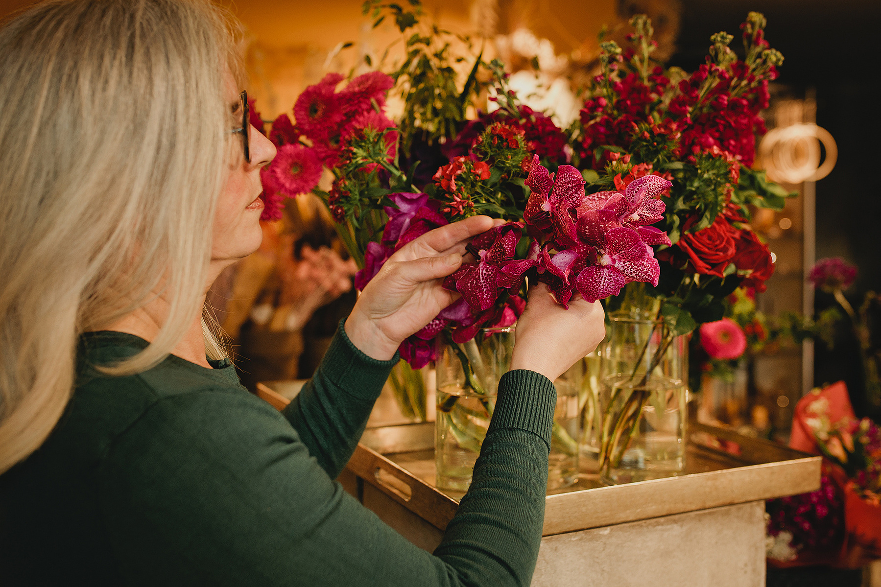 Eine Floristin arrangiert die Blumen in ihrem Laden, während die Businessfotografin aus Berlin ungestellte Fotos von ihr macht. 