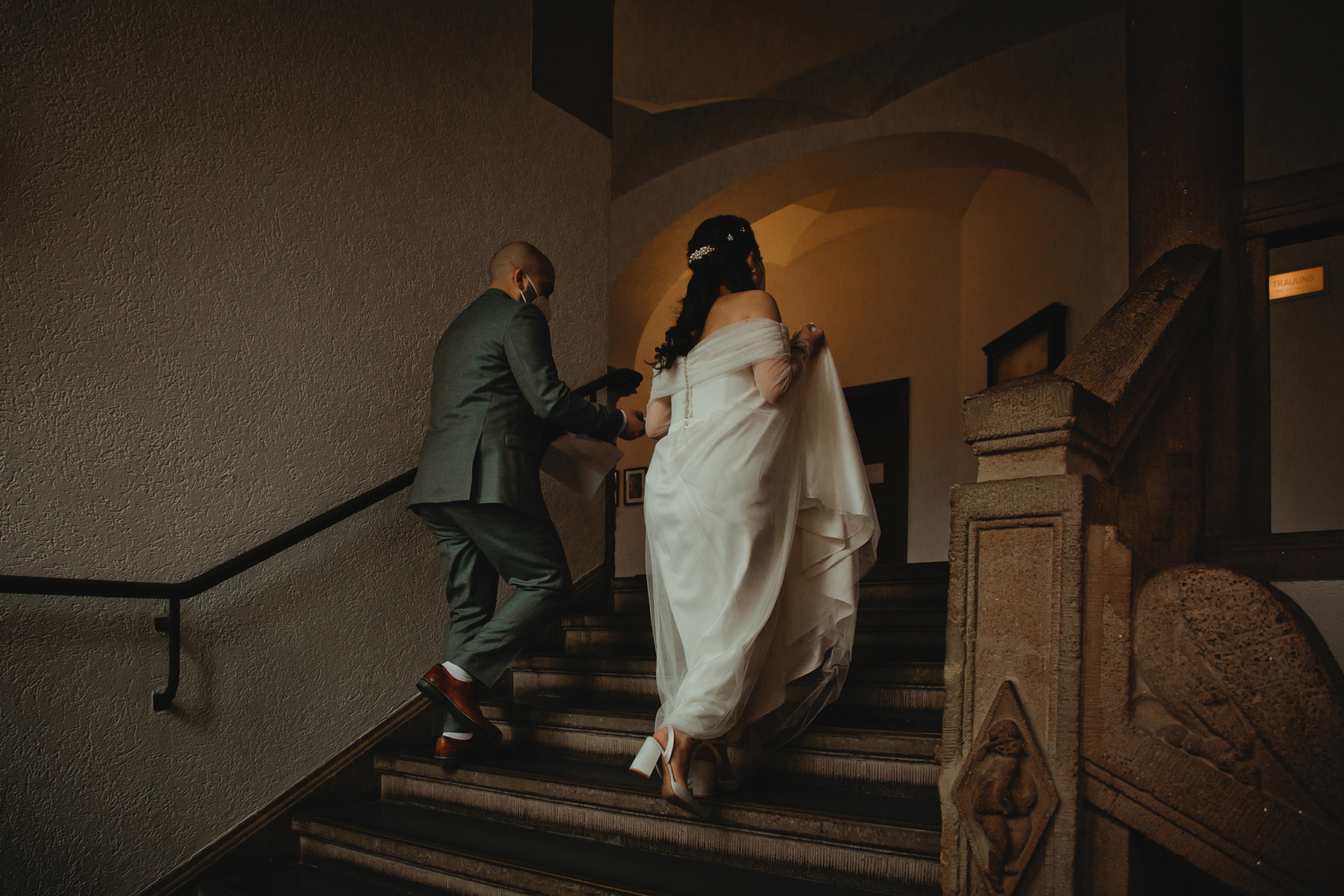Braut und Bräutigam schreiten auf dem Weg zum Trauzimmer über die große Treppe im Standesamt Berlin-Reinickendorf. 