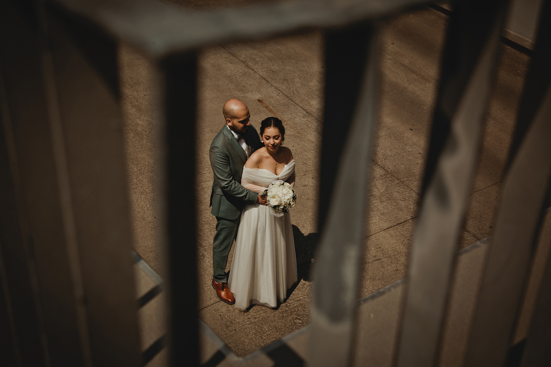 Die Hochzeitsfotografin aus Berlin fotografiert beim Brautpaarshooting für eine besondere Perspektive durch ein Geländer hindurch.