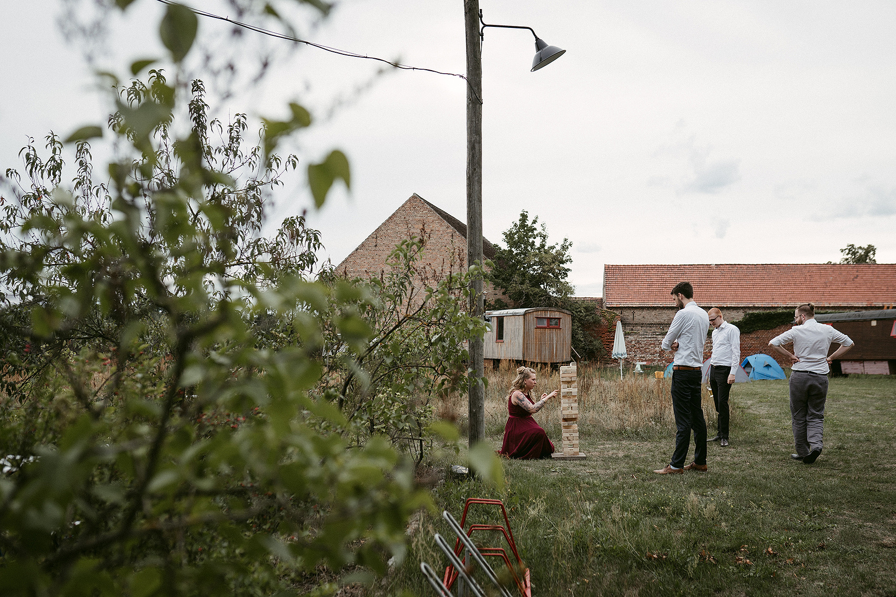 Entspannte Gartenhochzeit in Brandenburg. Die Hochzeitsgäste spielen Riesenjenga auf der Wiese.