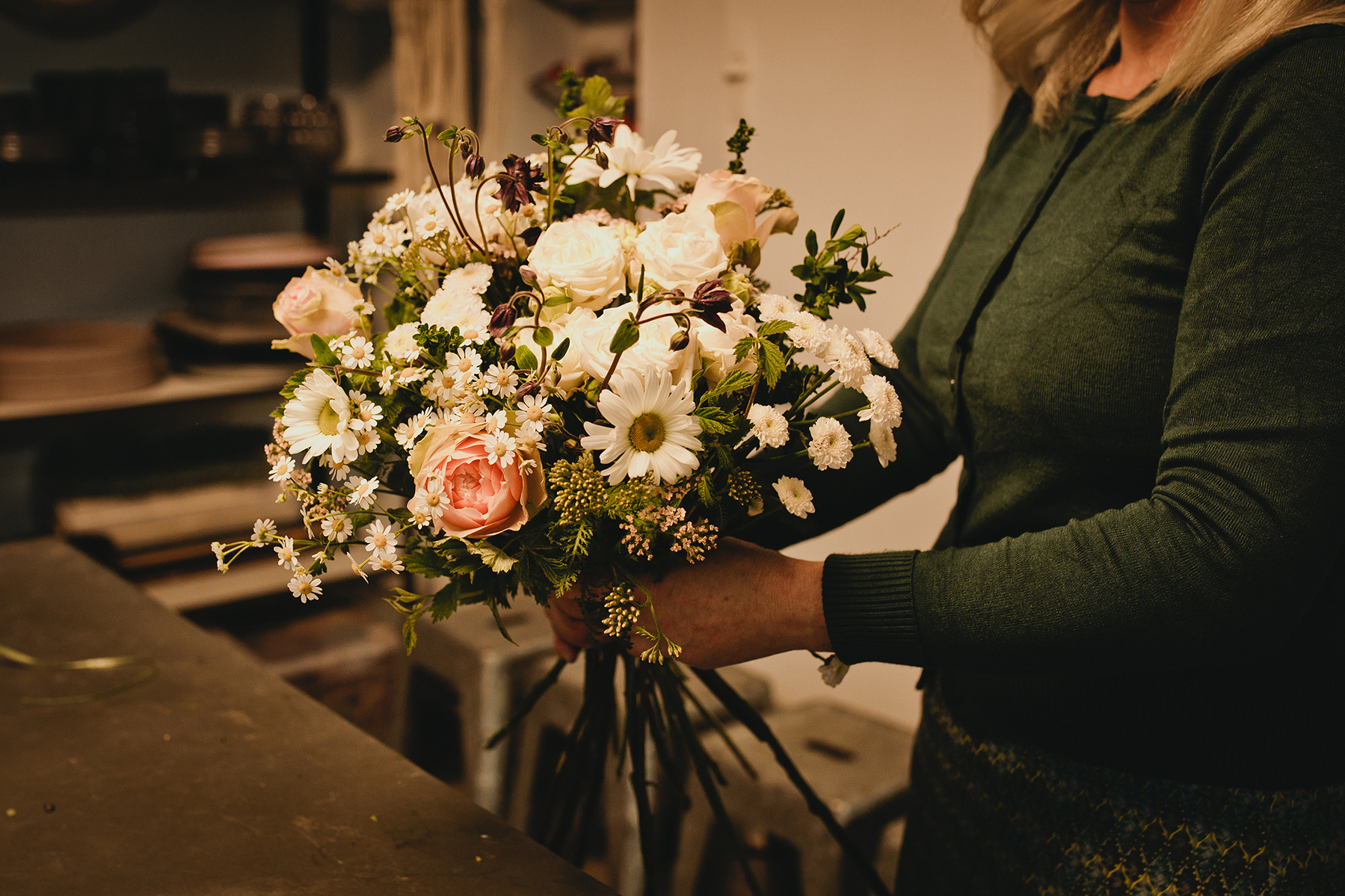 Businessfotos in Berlin mit Liebe zum detail. Eine Floristin bindet in ihrer Werkstatt einen Blumenstrauß. 