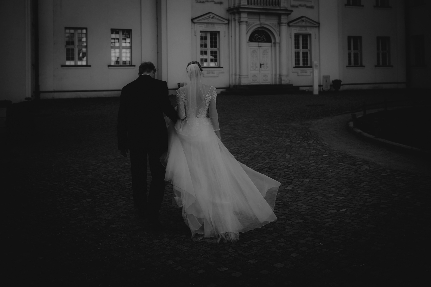 Ein Brautpaar läuft mit wehenden Kleidern auf das Schloss Köpenick zu.