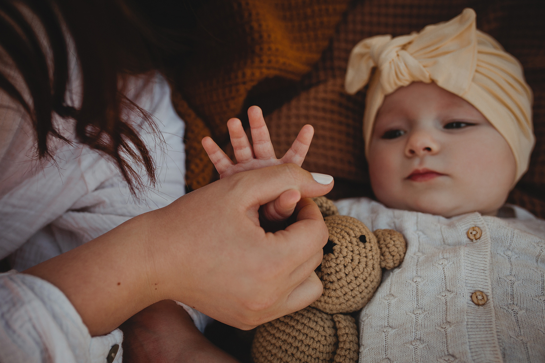 Detailaufnahme von einem ungestellten Familienshooting. Die kleine Tochter greift nach der Hand ihrer Mutter.