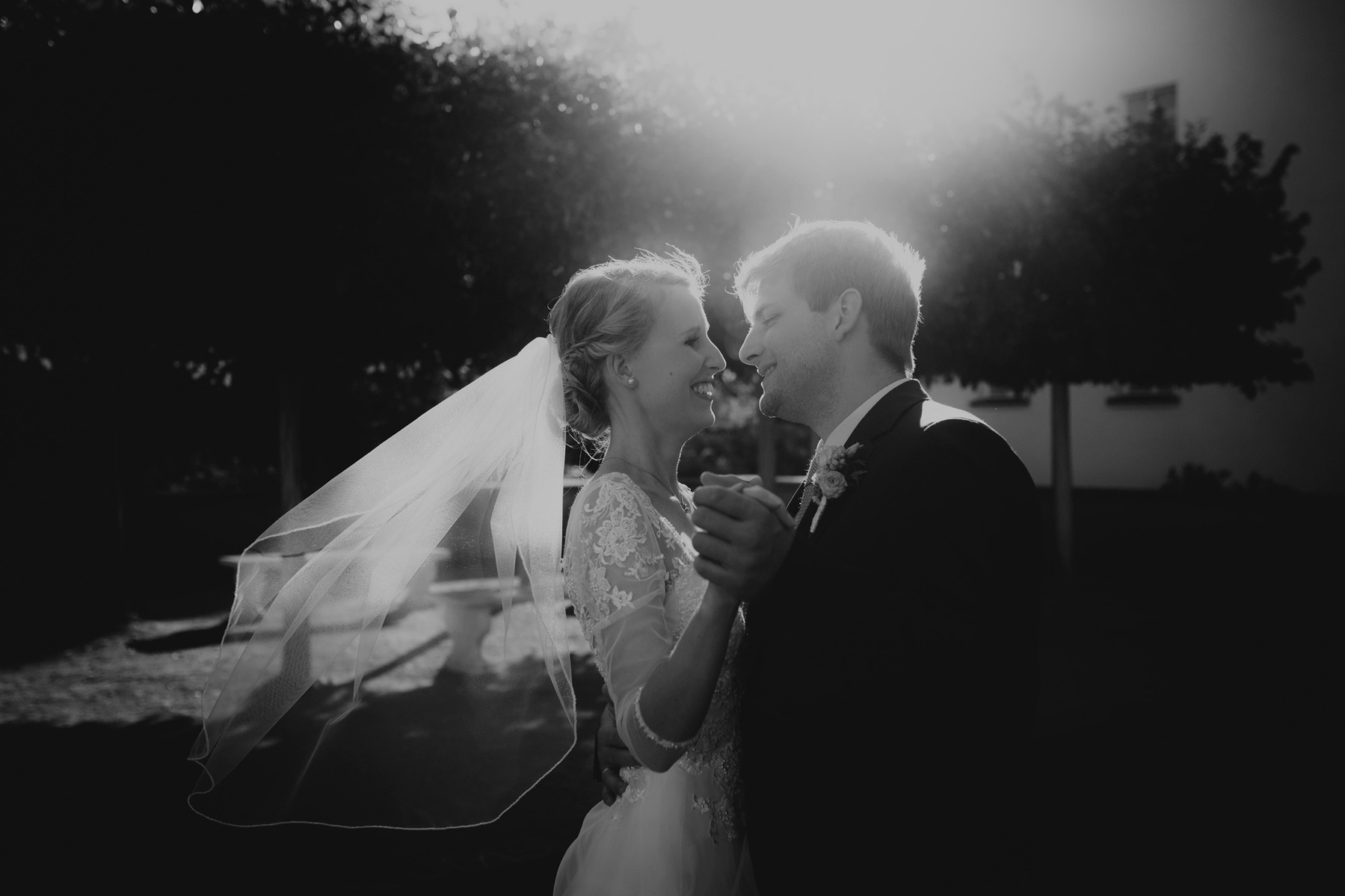 Beim Hochzeitstanz in der Abendsonne wirbelt der Bräutigam seine Braut lachend umher während ihr Schleier im Wind weht. 
