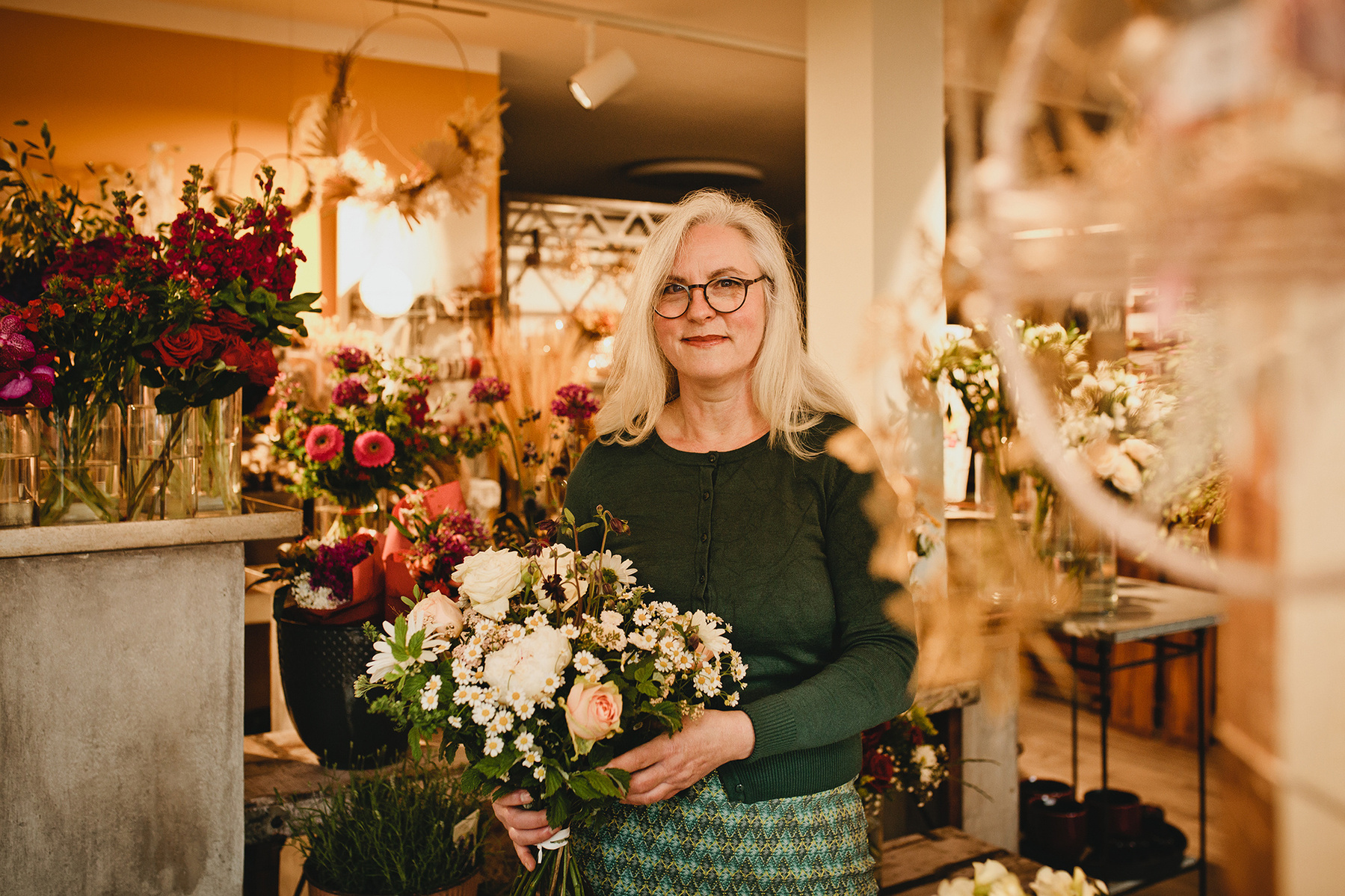 Die Floristin Manuela posiert mit einem Blumenstrauß für Businessfotos in ihrem Blumenladen in Berlin. 