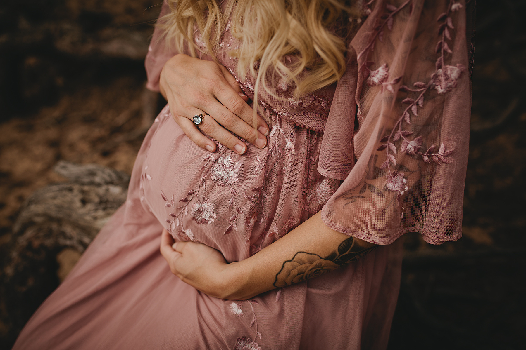 Jana trägt ein romantisches Umstandskleid im Bohostil und streichelt sich über ihren Babybauch.