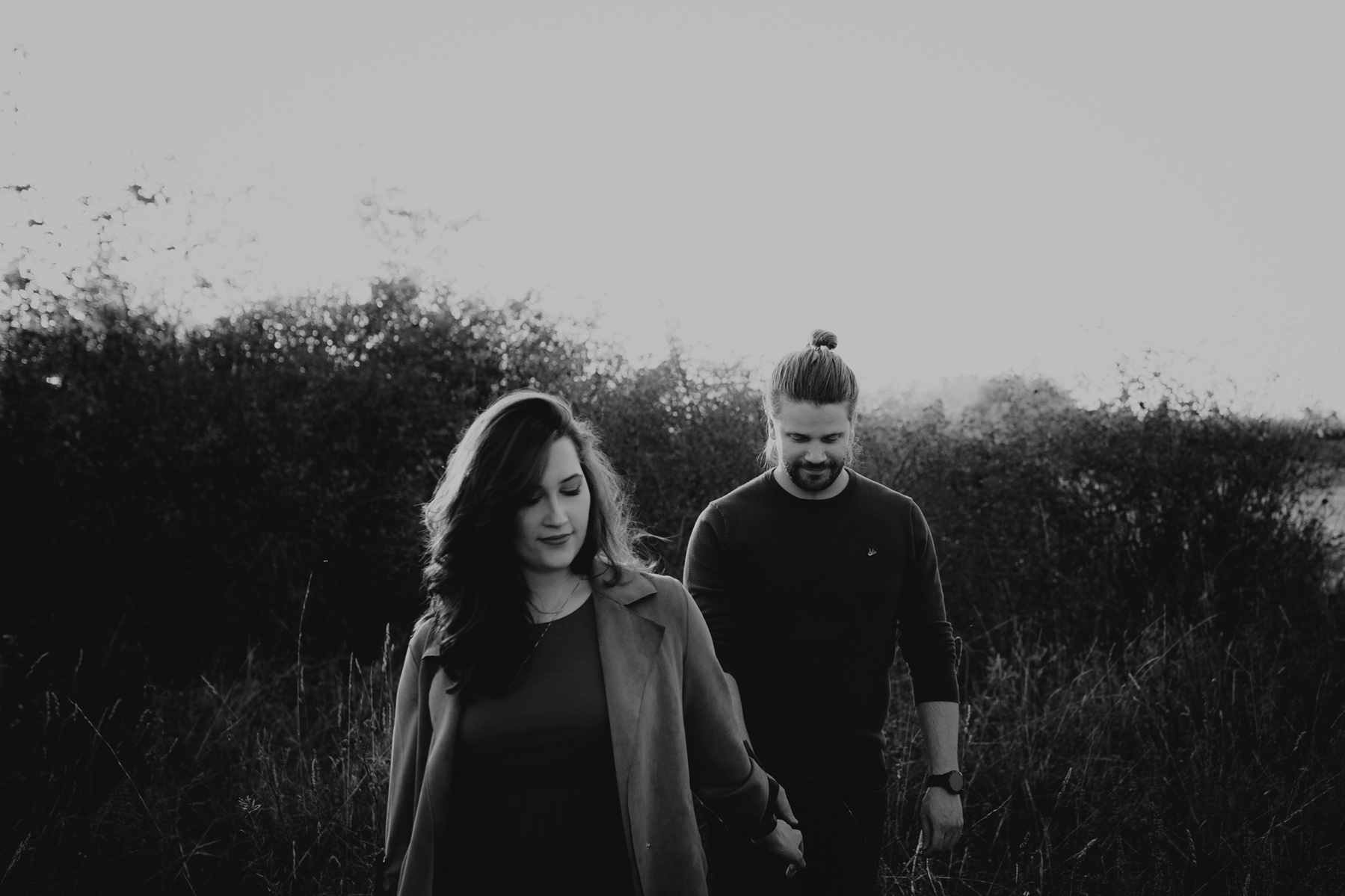 Schwarz-weiß Aufnahme von Mann und Frau, die beim Fotoshooting in der Natur spazieren gehen.