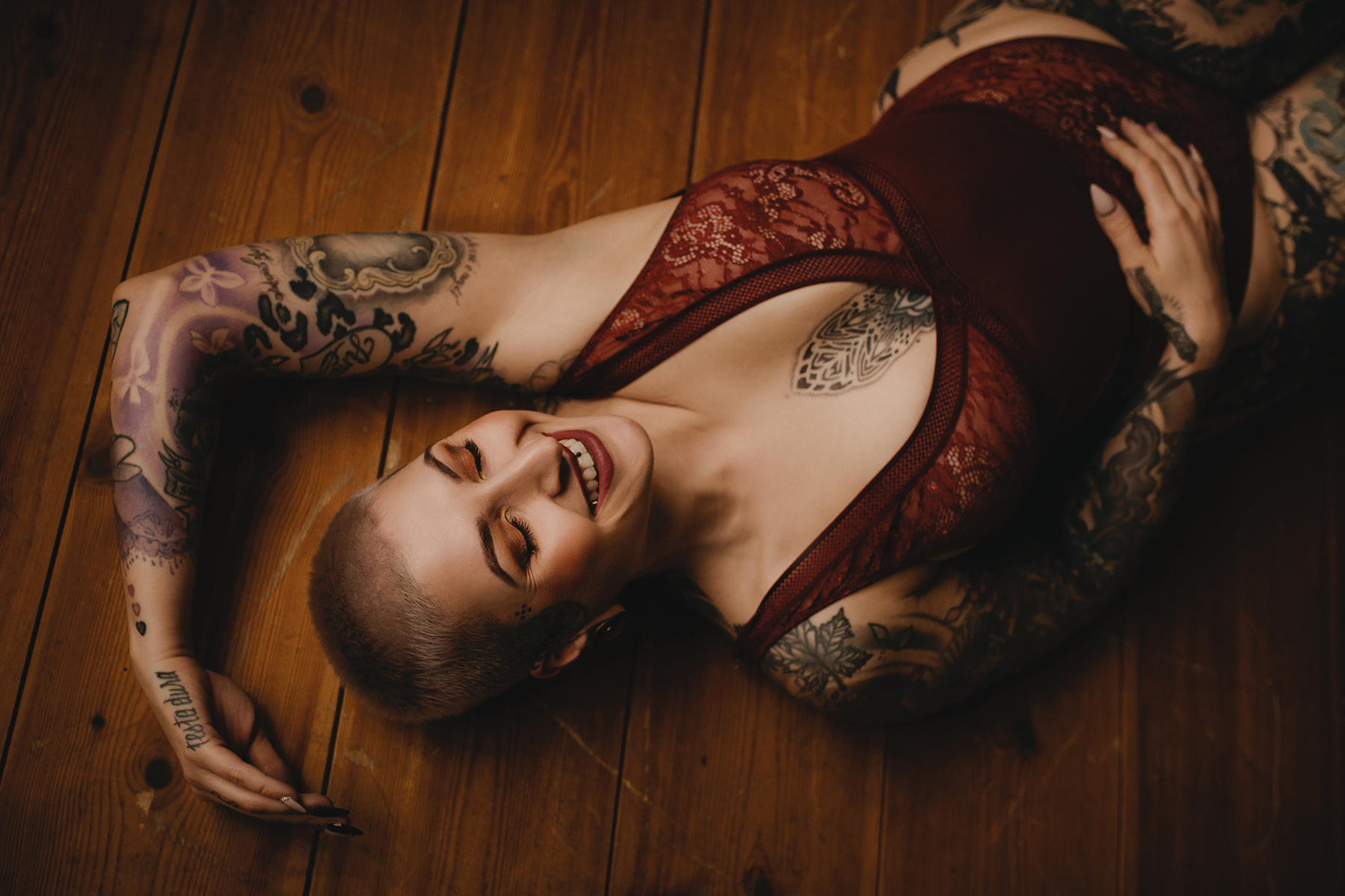 Eine Frau räkelt sich beim Boudoirshooting auf dem Bodeln. Ein natürliches Lächeln umspielt ihre Lippen.