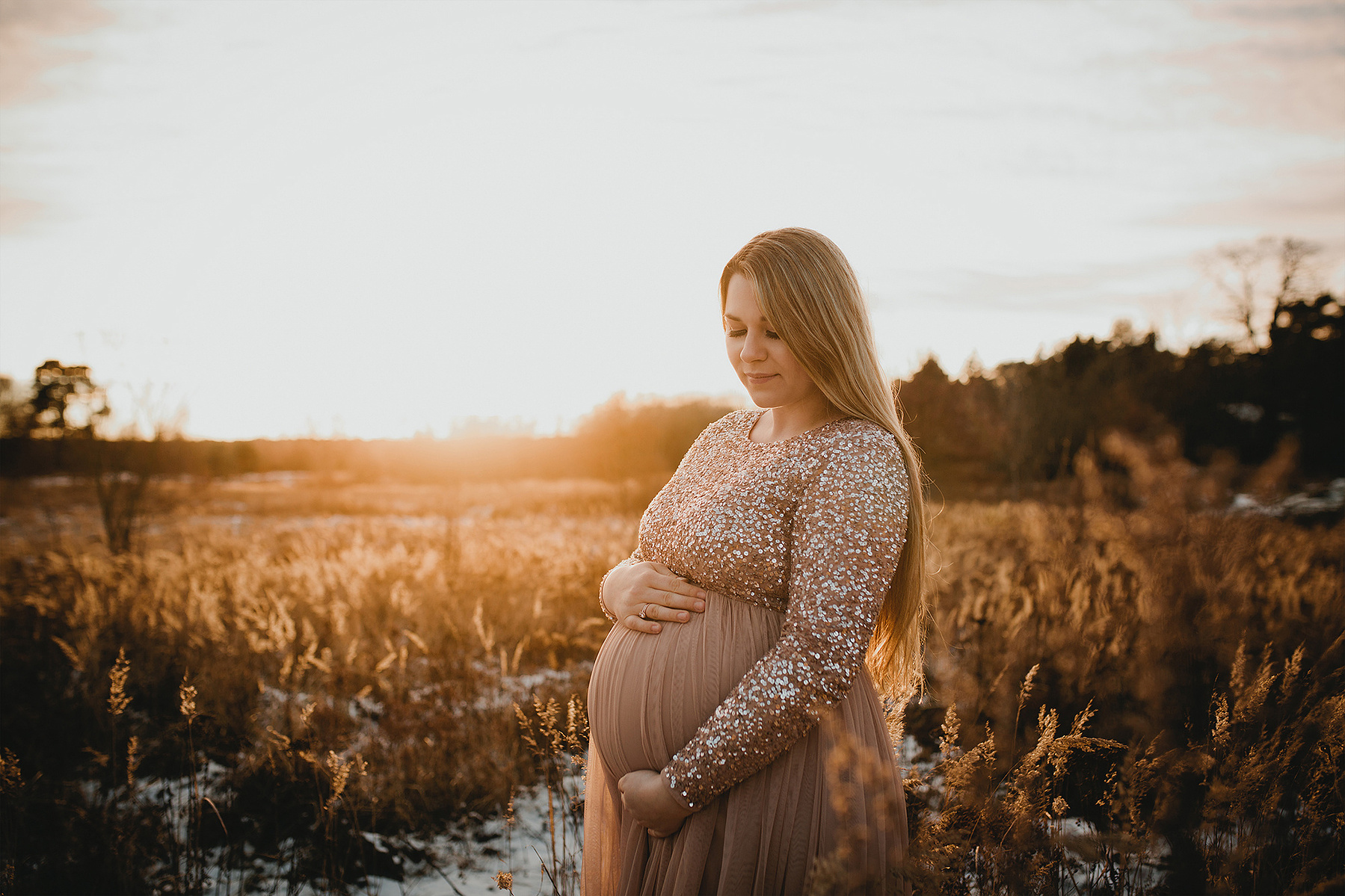 Liebevoll blickt Eileen auf ihren Babybauch, während die Fotografin natürliche Schwangerschaftsfotos in Berlin macht.