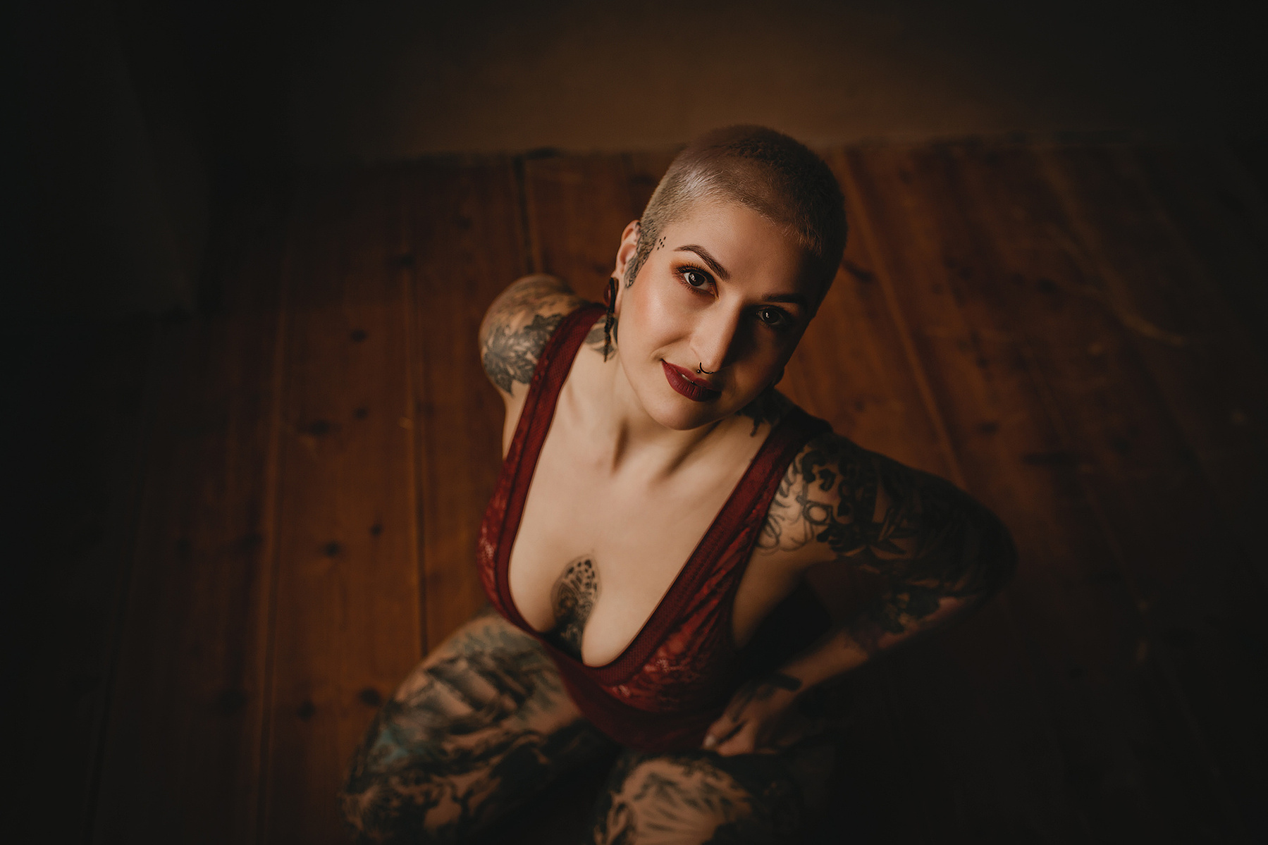 Eine Frau in Dessous sitzt beim Boudoirshooting auf dem Boden und blickt in die Kamera.