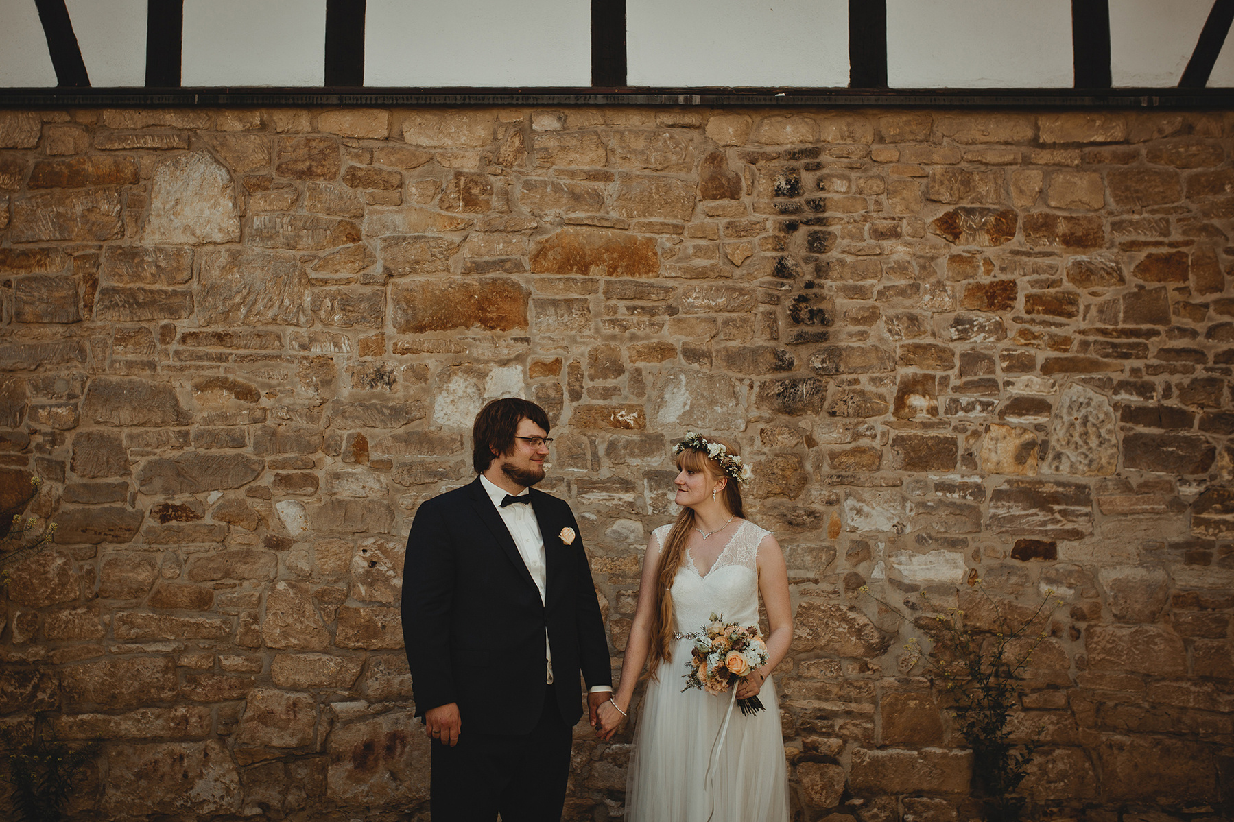 Ein Brautpaar posiert lächelnd für die Hochzeitsfotografin in Weißenfels vor einem Fachwerkhaus.