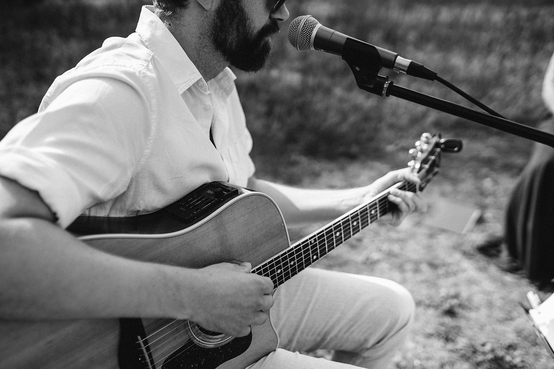 Der Hochzeitsmusiker spielt bei der freien Trauung im Grünen auf seiner Gitarre.