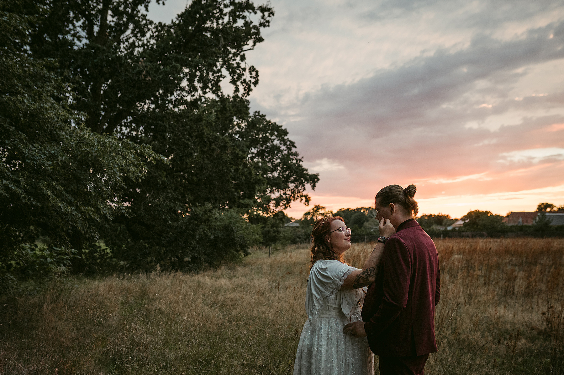 Beim Sunset Couple Shoot am Hochzeitsabend steht das Brautpaar im Sonnenuntergang auf einer Wiese.