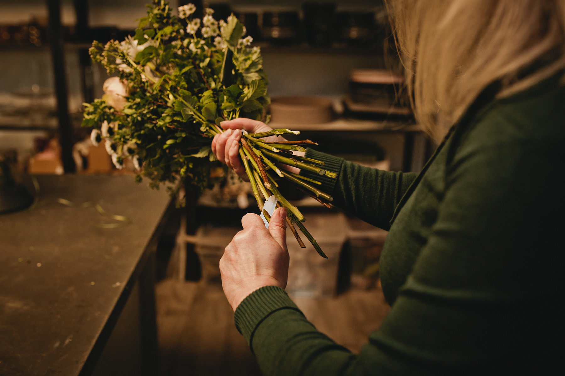 Eine Floristin kürzt während einer authentischen Businessreportage in Berlin die Stängel der Blumen. 