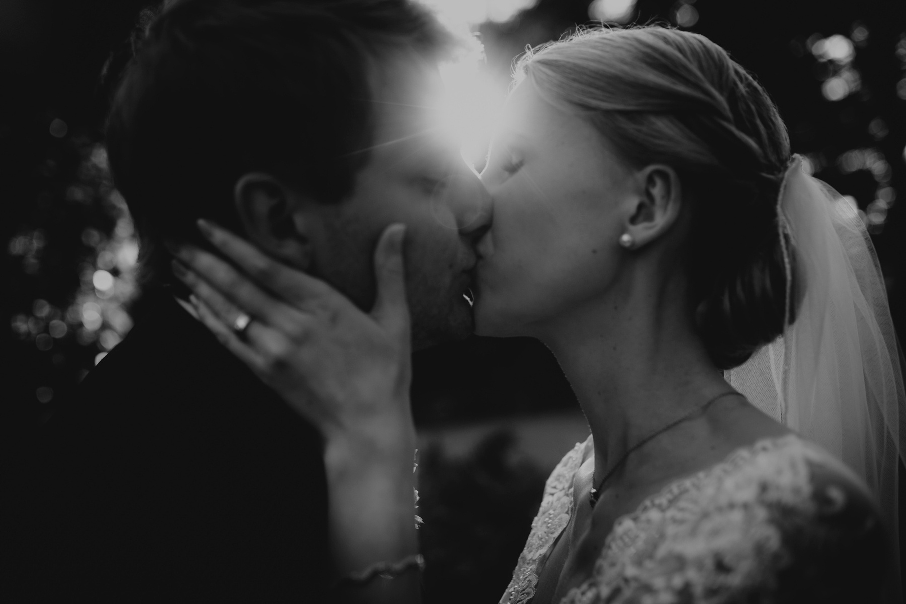 Stimmungsvolle Gegenlichtaufnahme eines Brautpaars während des Kusses, von einer Berliner Hochzeitsfotografin verewigt. 