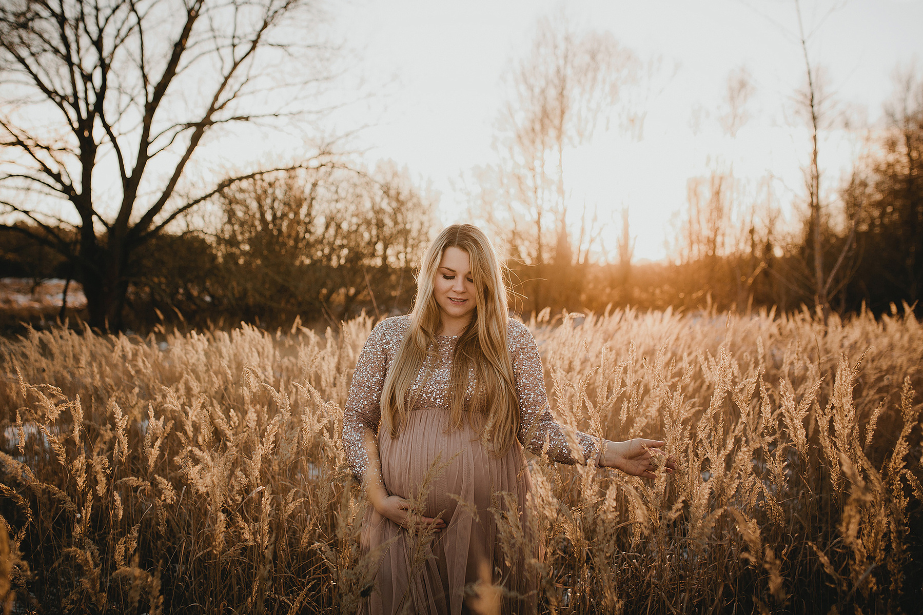 Eine schwangere Frau läuft beim Fotoshooting in Berlin durch eine verträumte Szenerie in der Natur.