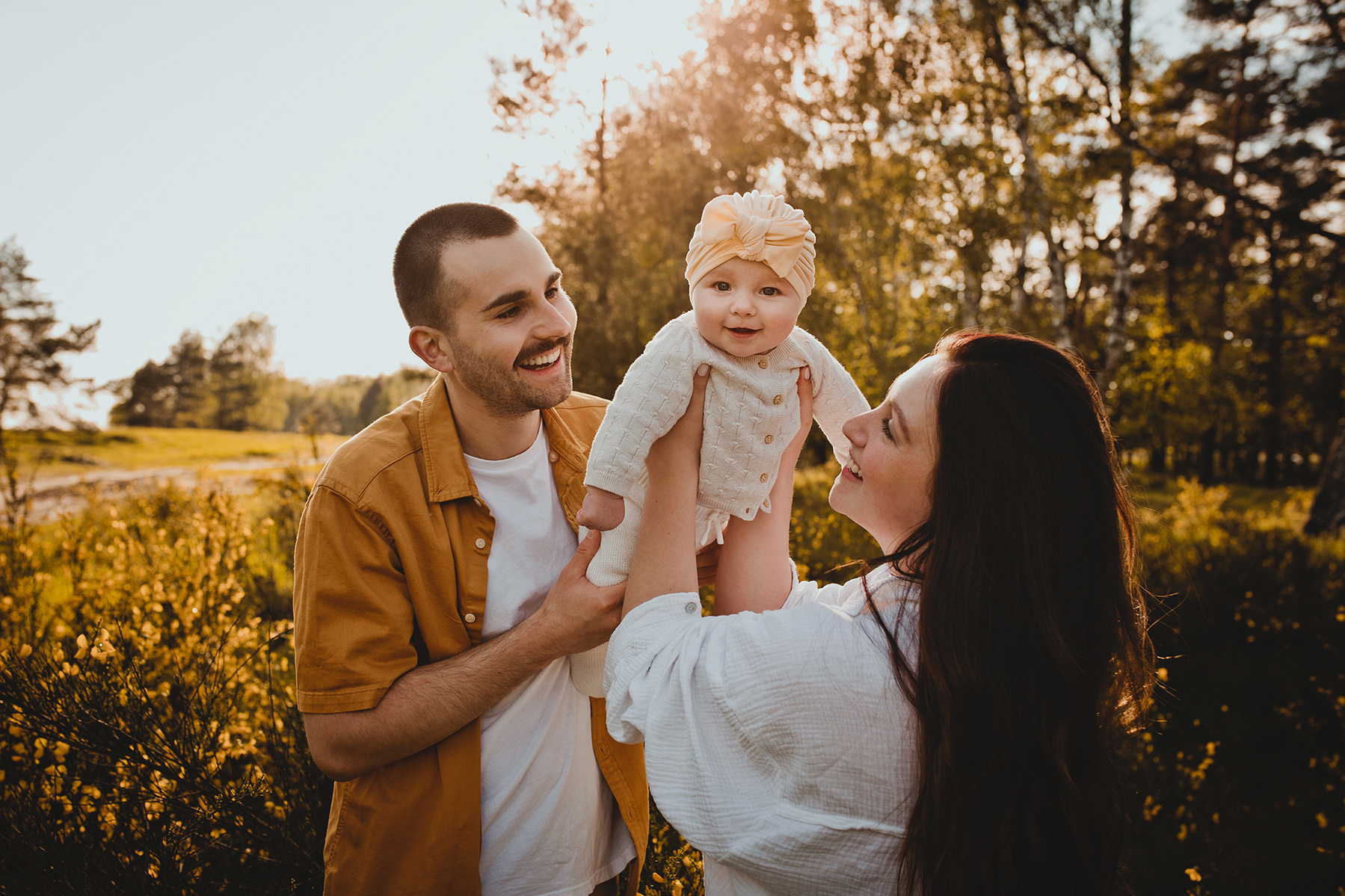Eine Familie spielt beim Fotoshooting in der Natur ausgelassen miteinander.