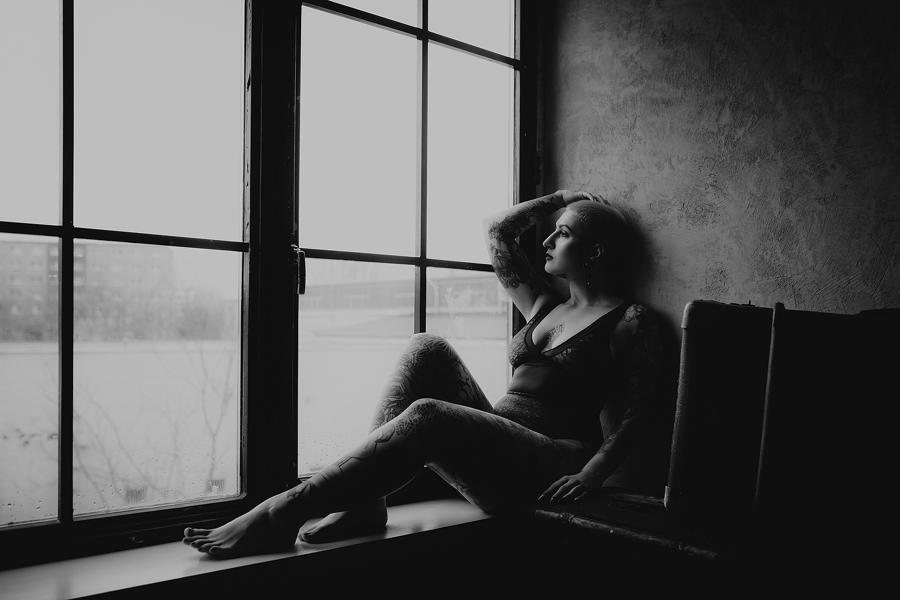 Jacky sitzt im Boudoir Fotostudio in sinnlicher Pose am Fenster und blickt hinaus.