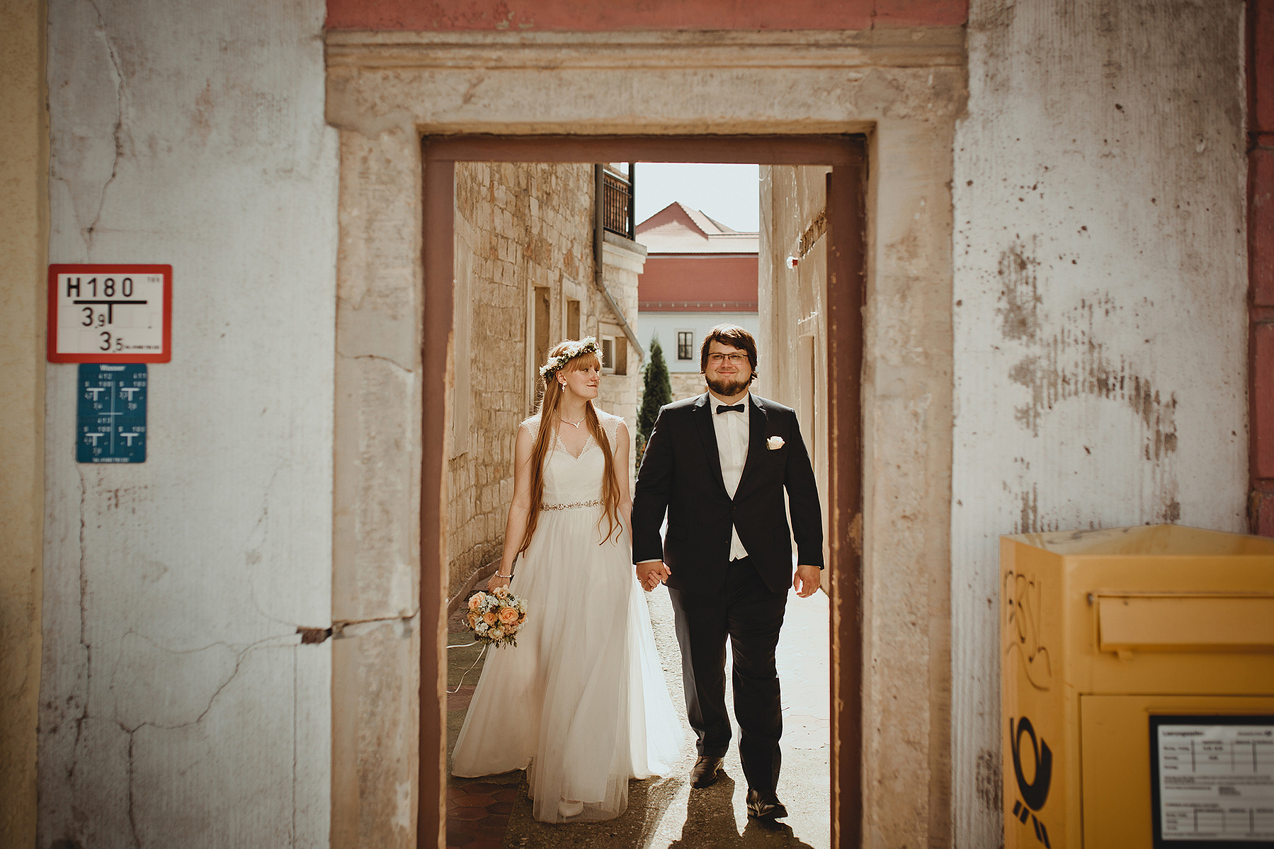 Ein Brautpaar spaziert für ungestellte Hochzeitsfotos in Weißenfels durch eine Gasse. 