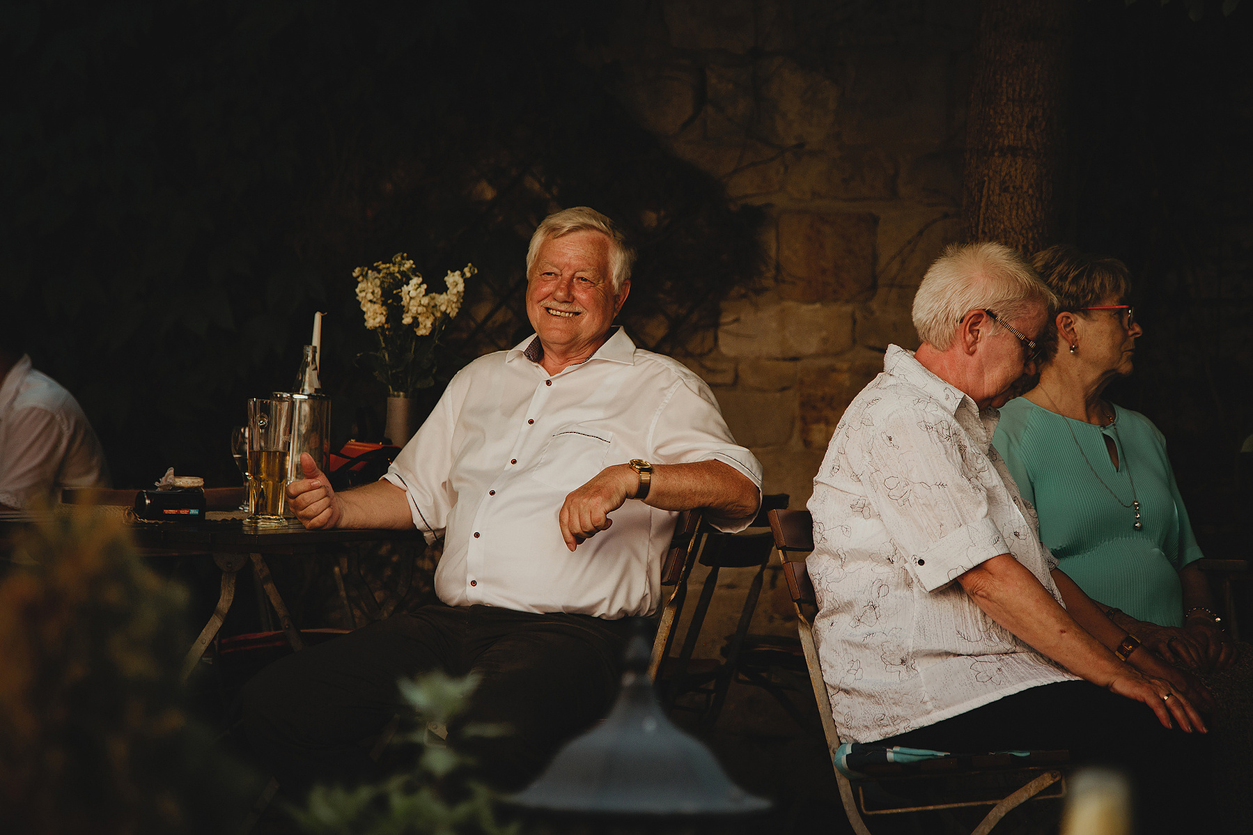 Ein älterer Hochzeitsgast lächelt der Hochzeitsfotografin freundlich zu. 