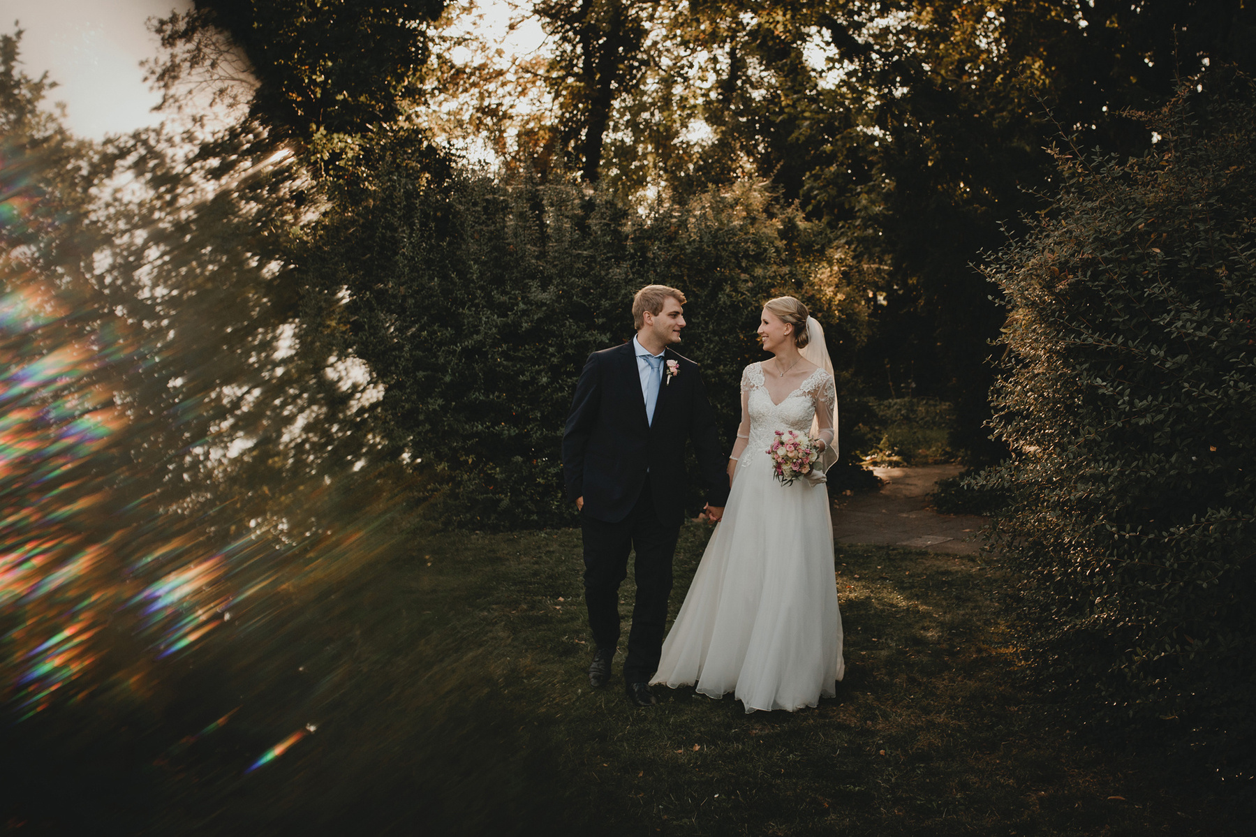 Ein Brautpaar spaziert für moderne Hochzeitsfotos durch den Schlosspark in Köpenick.