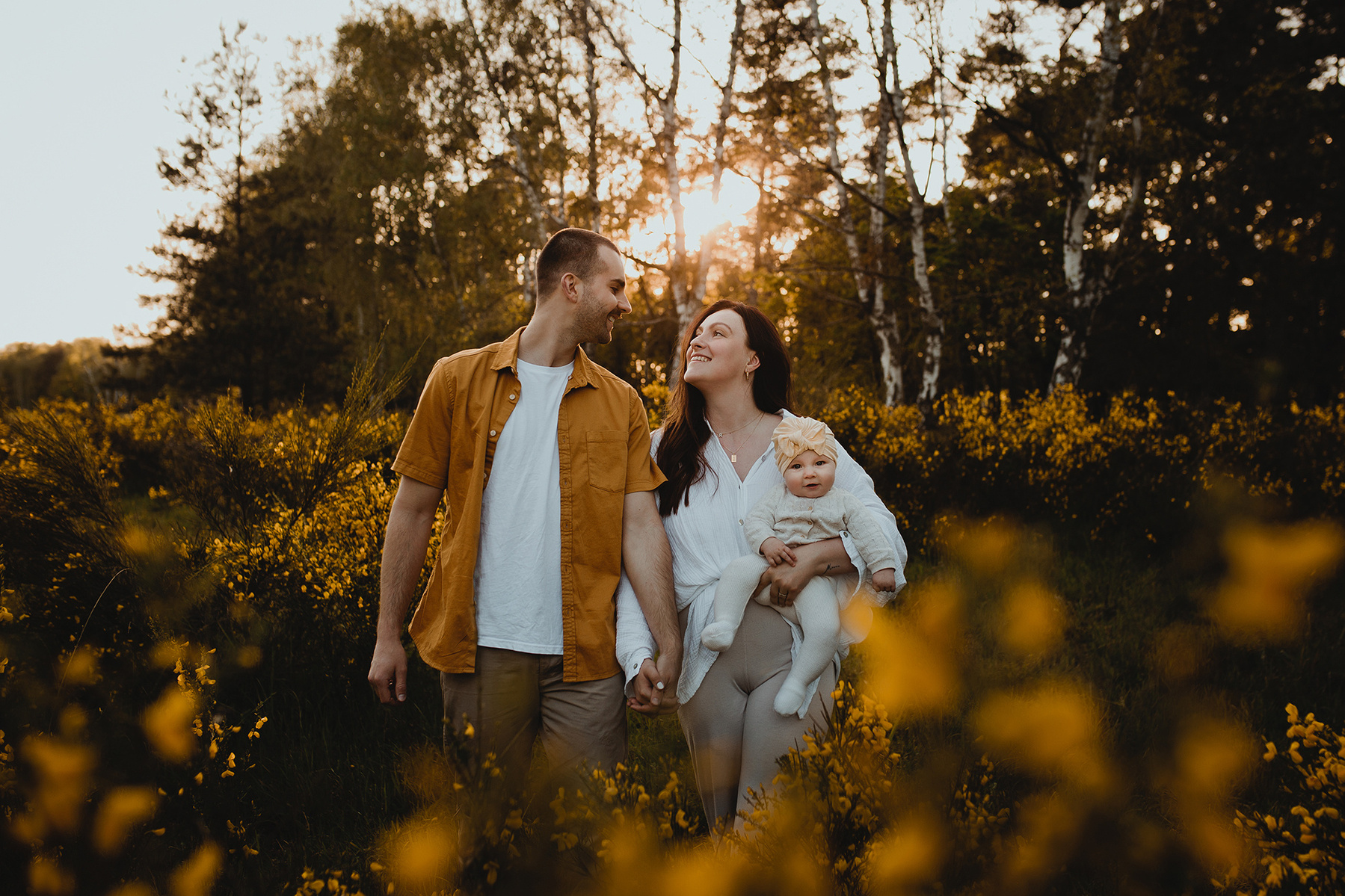 Die Eltern blicken sich beim Familienshooting im Sonnenuntergang verliebt in die Augen. 