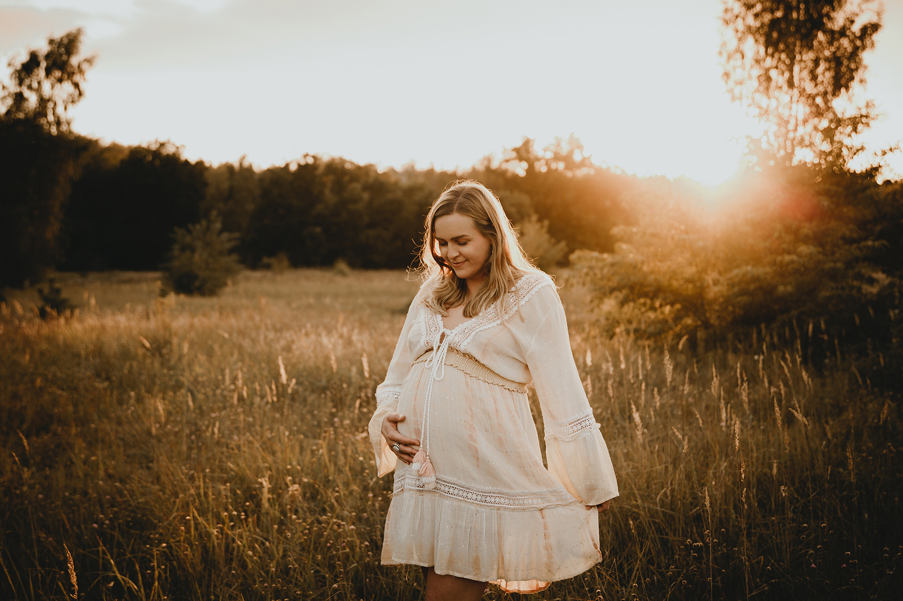 Nathalie genießt die besondere Zeit ihrer Schwangerschaft bei einem Babybauch Fotoshooting im Sonnenuntergang.