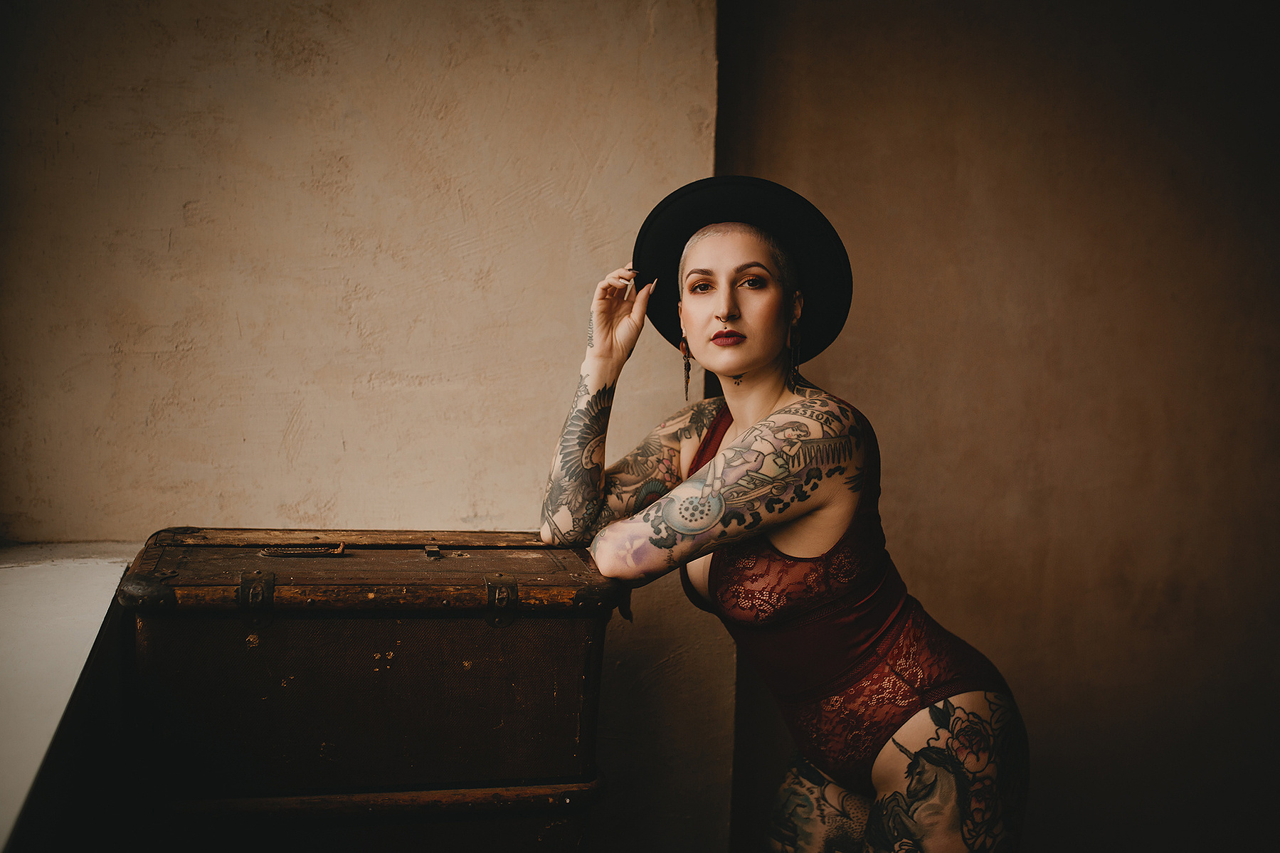 Eine Frau mit Tattoos posiert für authentische Boudoirfotos in Berlin in einem Fotostudio.