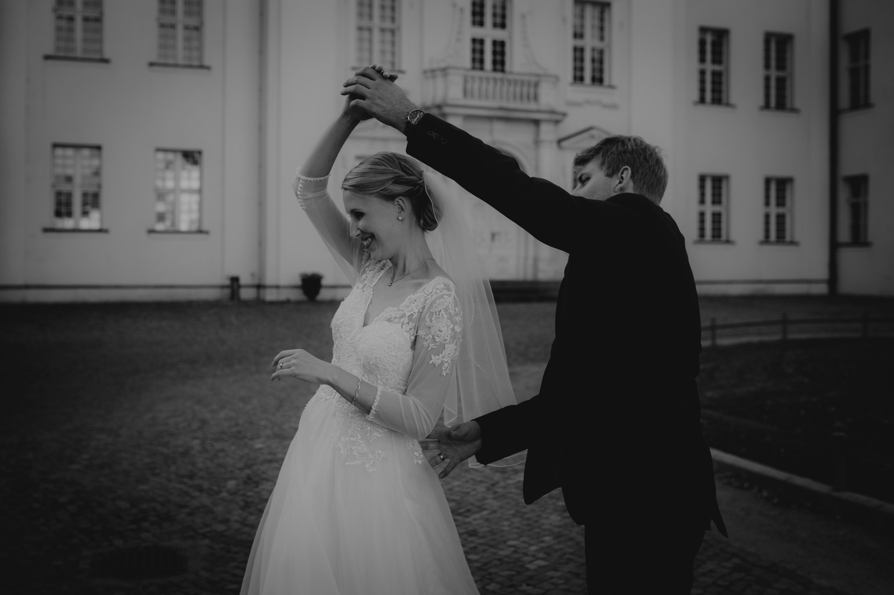 Braut und Bräutigam tanzen ausgelassen während ihres Paarshootings am Hochzeitstag.