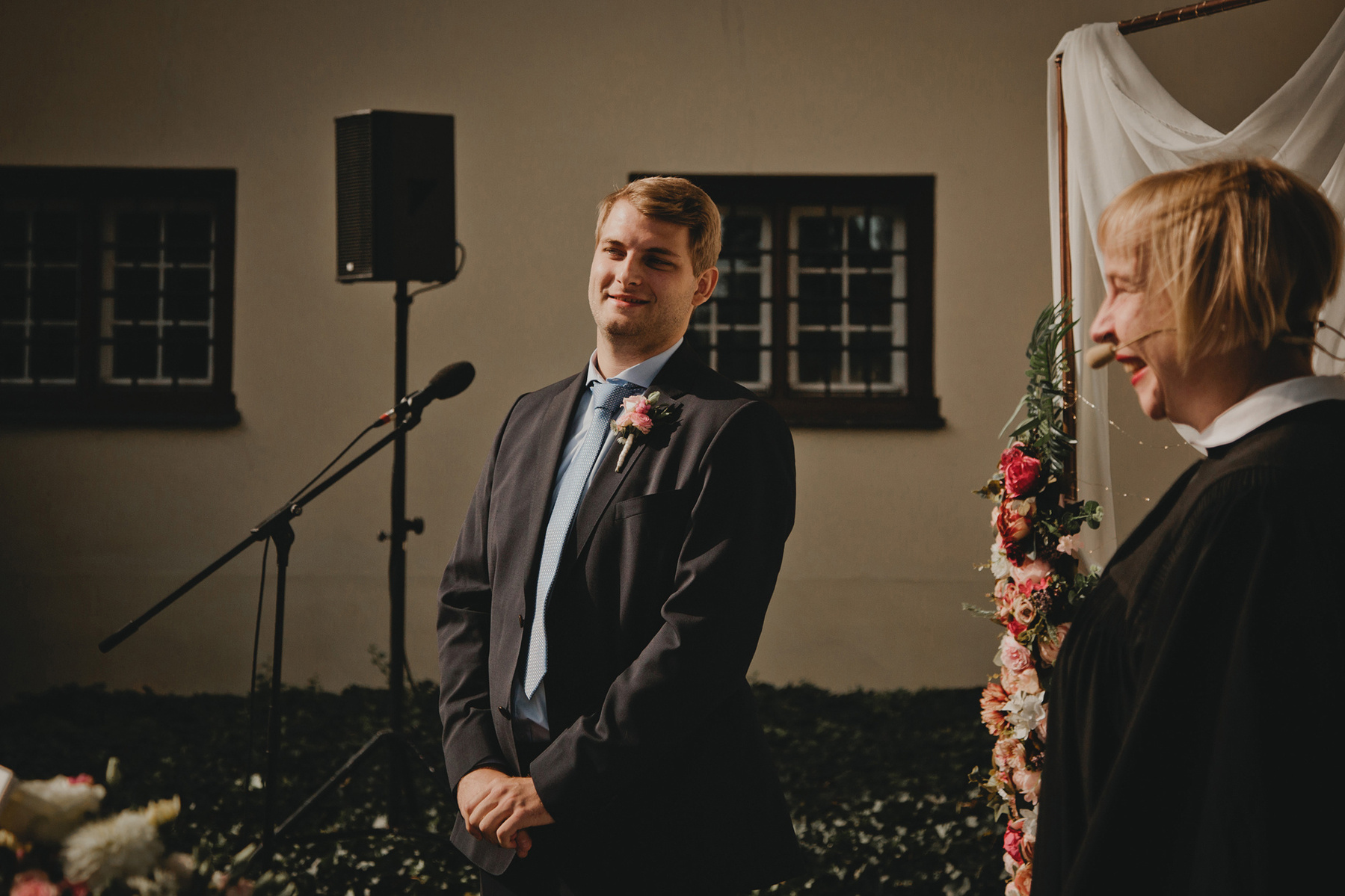 Der Bräutigam im blauen Hochzeitsanzug sieht seine Braut beim First Look zum ersten Mal am Hochzeitstag.