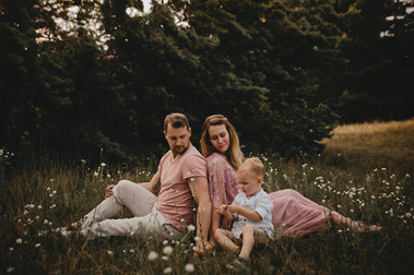Eine Familie mit Outfits im Bohostil sitzt für natürliche Familienfotos auf einer Blumenwiese in Brandenburg.