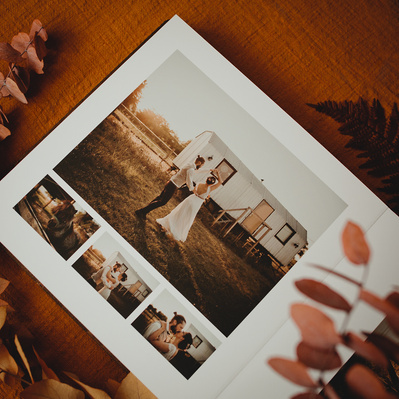 Ein aufgeklapptes Hochzeitsalbum mit Fotos einer Boho Hochzeit wird von Trockenblumen eingerahmt.