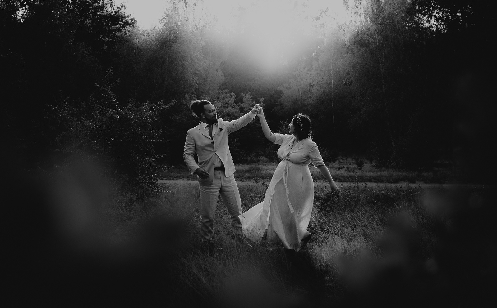 Braut und Bräutigam tanzen für ihre ungestellten Hochzeitsfotos ausgelassen in der Natur.