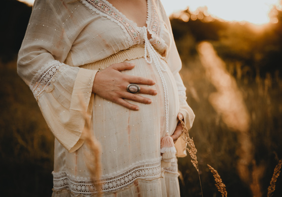 Eine werdende Mutter streichelt beim Schwangerschafts Fotoshooting in Berlin ihren Babybauch. 